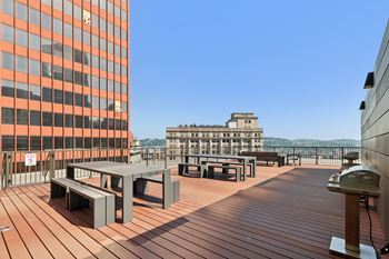 A wooden deck with benches and a table with a building in the background. at LiveWell Apartments, Pennsylvania